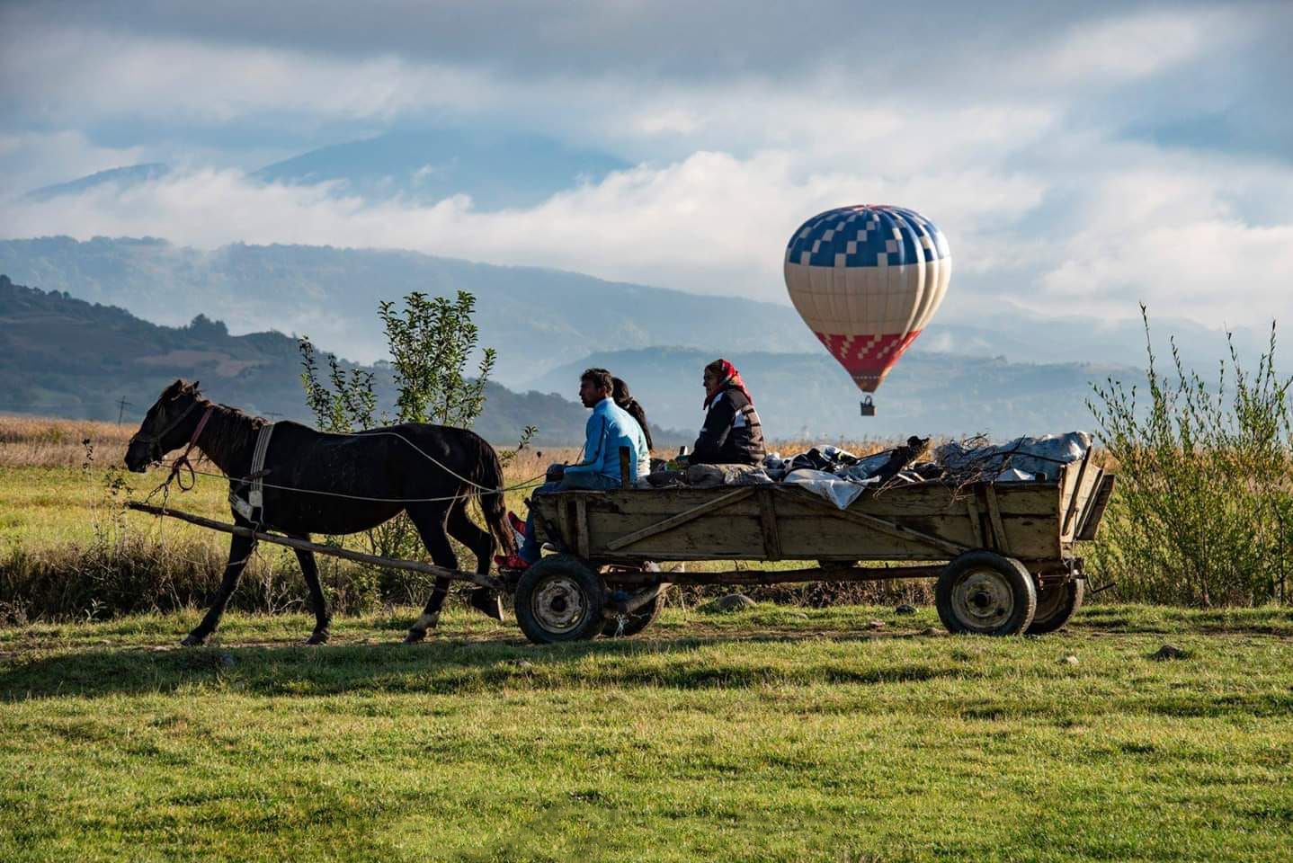 Teplovzdušný balón stúpajúci nad vidiekom – pokojná atmosféra a kontrast tradície a lietania.