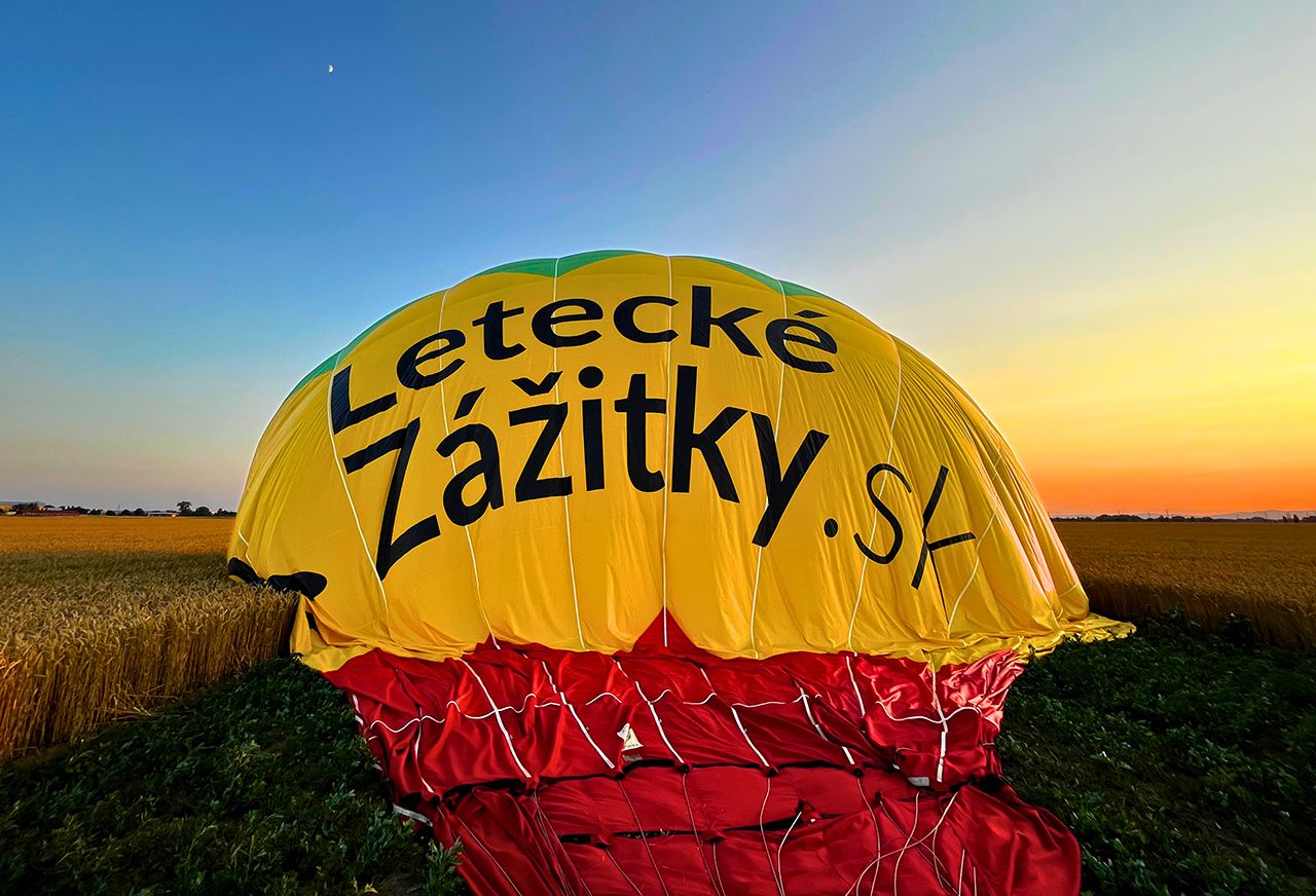 Balón po pristátí počas zlatej hodiny pri západe slnka – pokojný záver vyhliadkového letu.