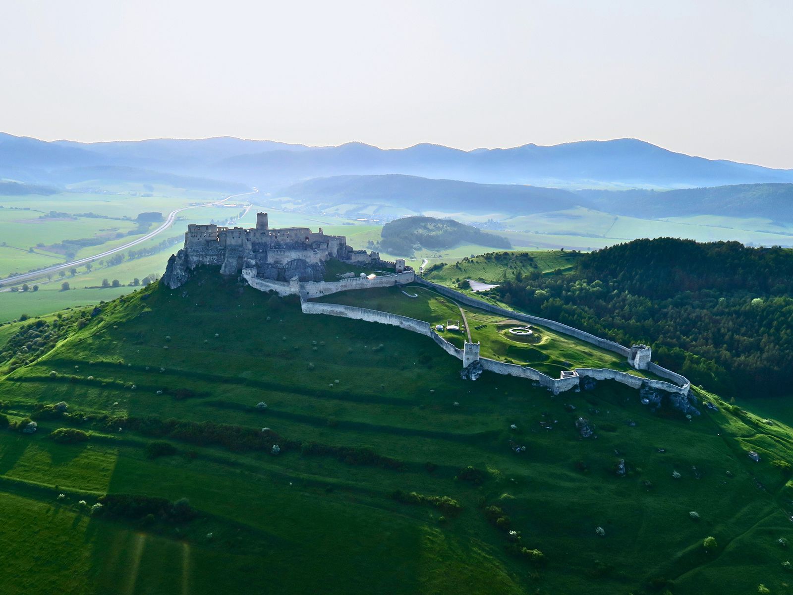 Letecký záber na monumentálny Spišský hrad obklopený krajinou Spiša – pohľad z vtáčej perspektívy počas vyhliadkového letu.