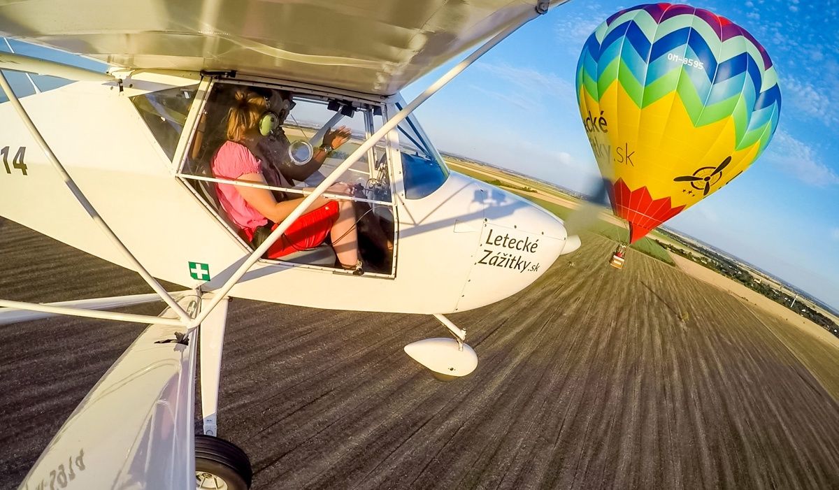 Let pilotom na skúšku v ľahkom lietadle s výhľadom na farebný teplovzdušný balón.